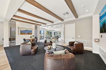 A spacious living room with brown leather furniture and a painting on the wall.